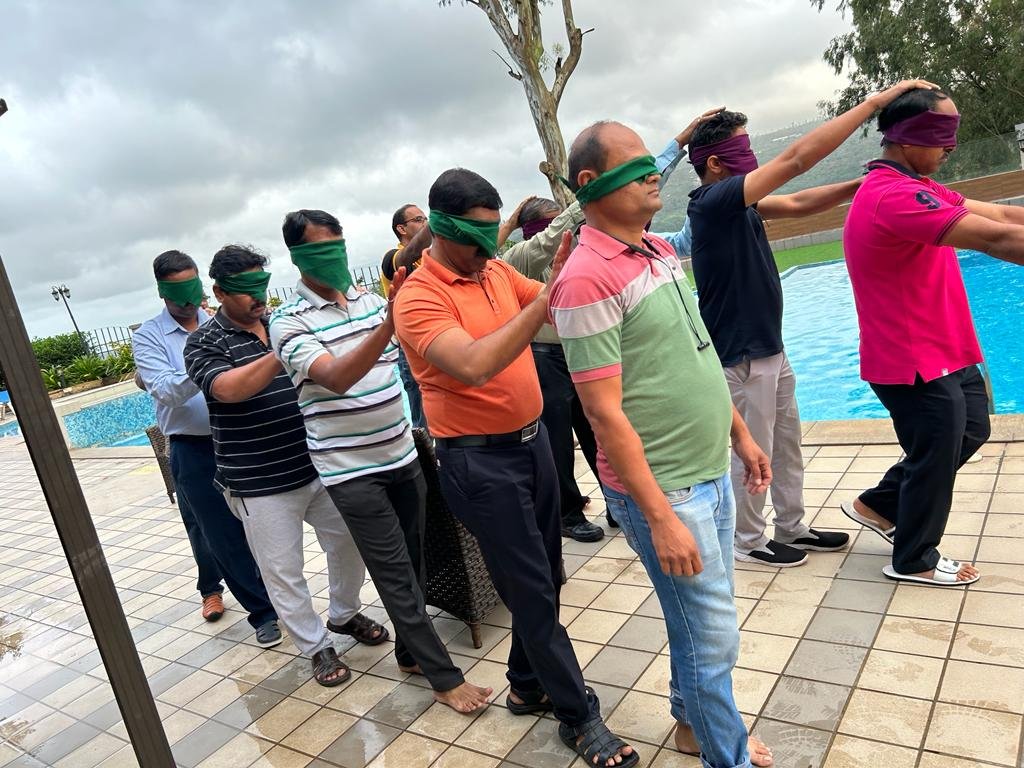 Participants completing a blindfolded trust-walk exercise poolside